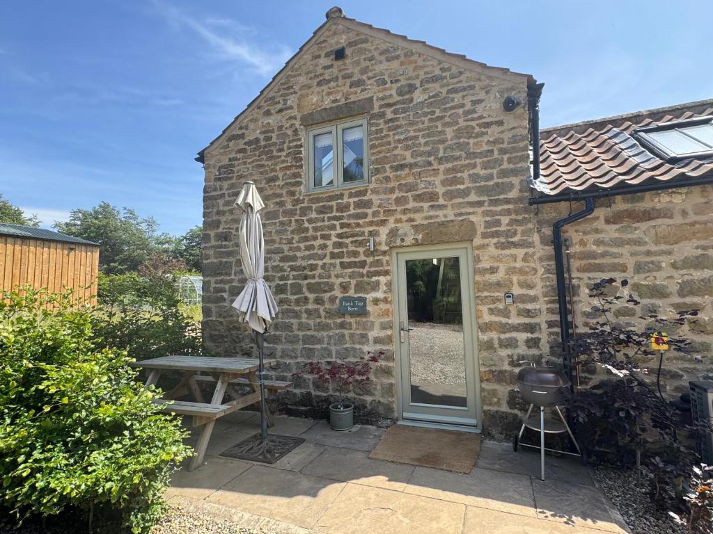 une maison en briques avec un parasol et une table dans l'établissement Bank Top Barn Cosy Self Catering 4 Guests, à Pickering
