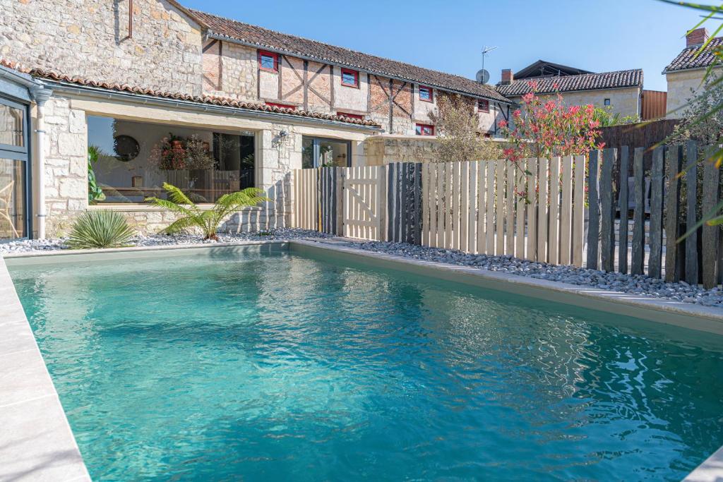 a swimming pool in front of a house at Gîte Lunaben-Maison en pierres avec piscine in Forges