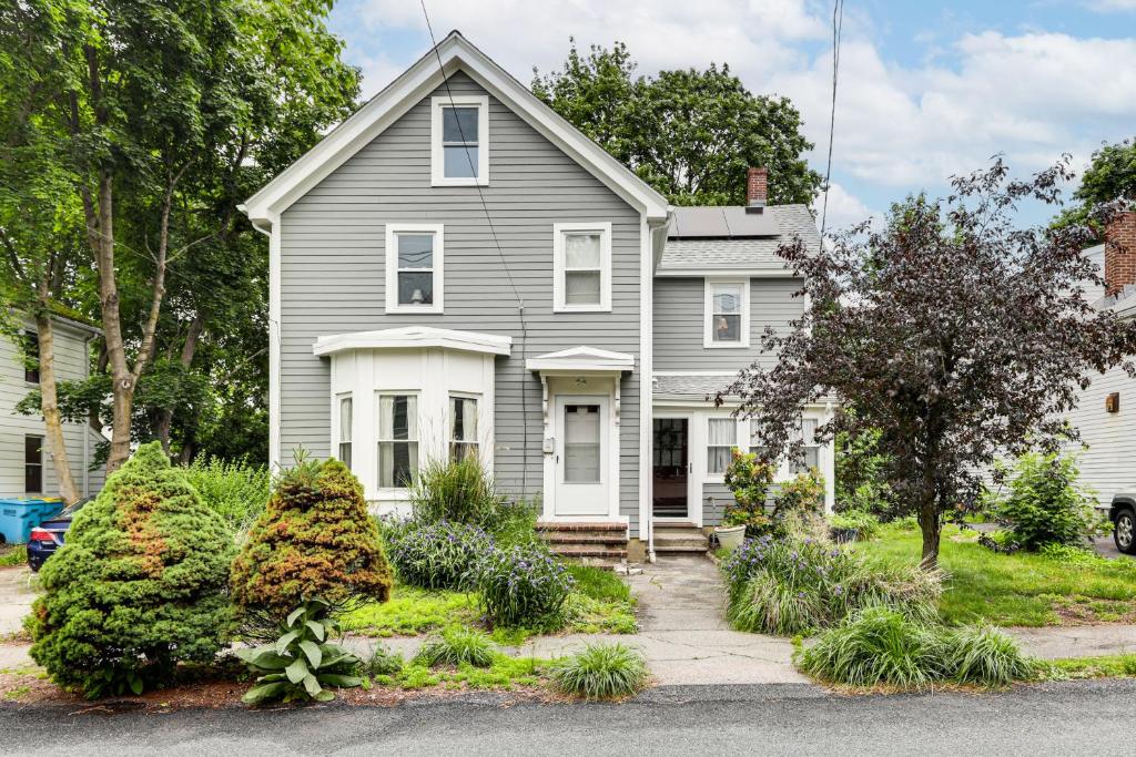 a gray house with white trim and bushes at 1 Mi to Needham Center Square: Pet-Friendly Apt! in Needham Heights