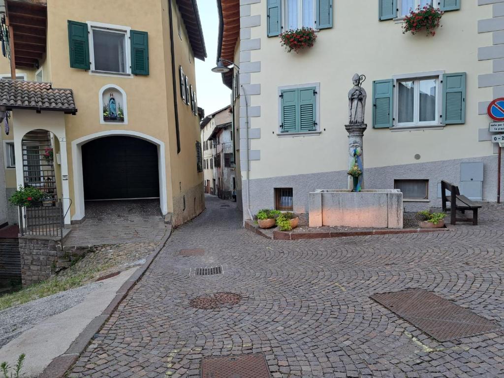 a cobblestone street in front of buildings with a statue at Casa Carraia Monolocale in Cembra