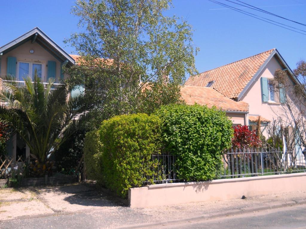 uma casa com arbustos verdes em frente a uma cerca em La Villa Vert Marine em Châtelaillon-Plage