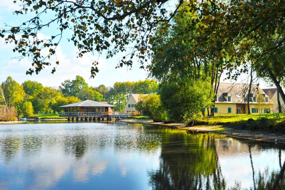 a view of a river with a building in the background at Camping maeva Respire Domaine de Sainte Montaine in Sainte-Montaine