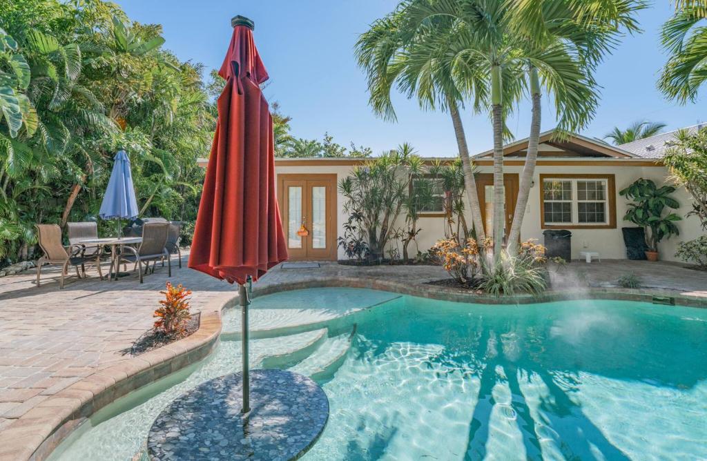a pool with an umbrella next to a house at Villa La Esperanza-Holmes Beach in Anna Maria Island