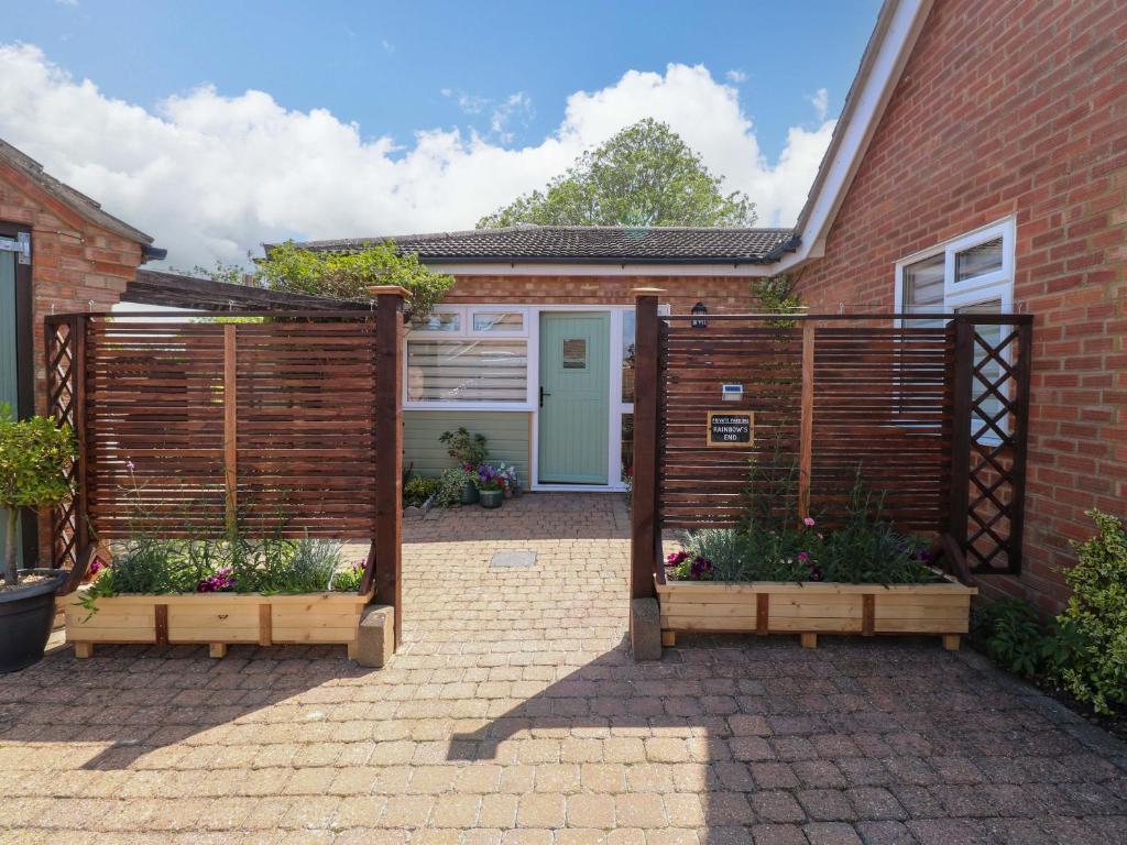 a garden with two wooden fences and a house at Rainbow's End in Swanton Morley