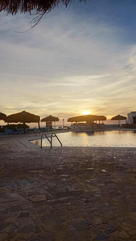 a group of umbrellas on a beach with the sunset at Romantic Chalete قرية الغرندل in Ras Sedr