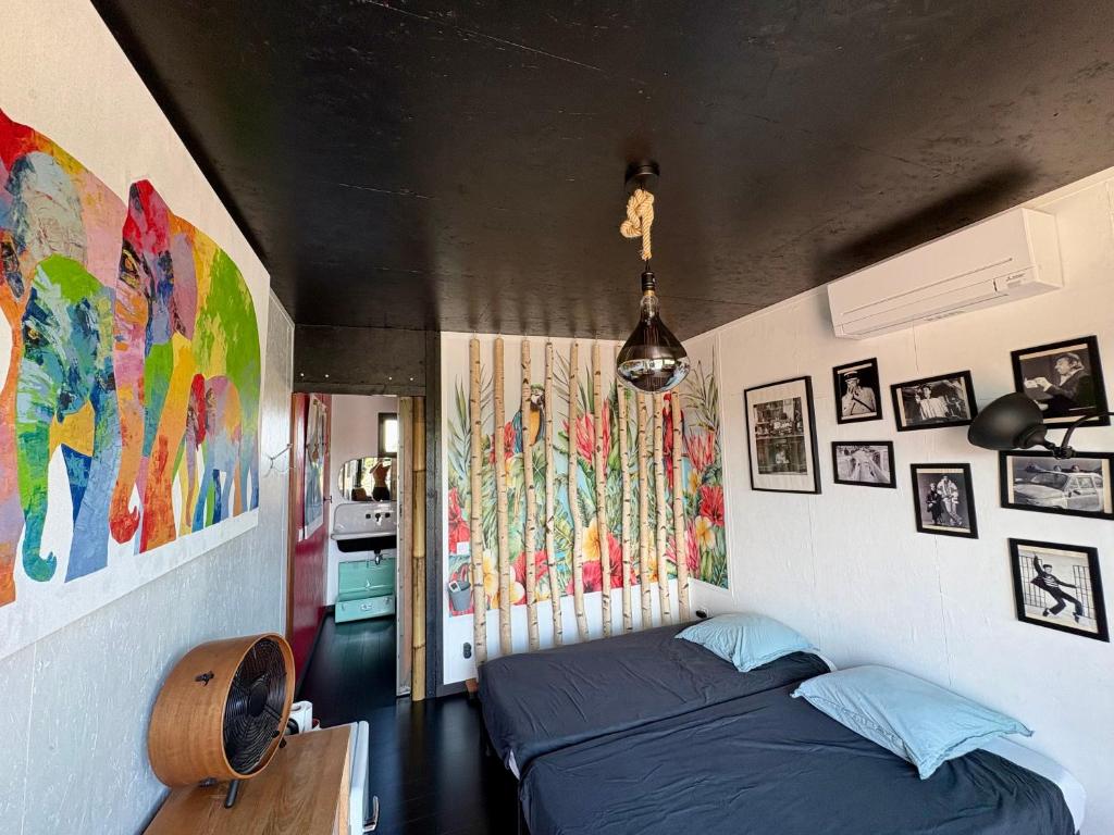 - une chambre avec un lit et des peintures sur les murs dans l'établissement Une adorable chambre SUR les toits, à La Celle-sous-Gouzon