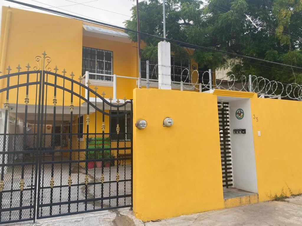 una casa amarilla con una valla negra y una puerta en Viento Casa los 4 elementos, en Cancún