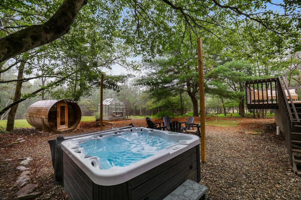 a hot tub in a yard next to a tree at 4 Br Mtn Cabin Sauna Hot Tub Fire Pit Putt Putt in Albrightsville