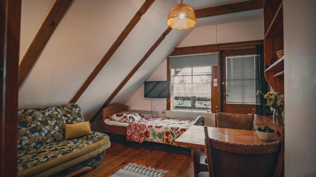 a room with a bed and a couch and a table at Pokoje Gościnne Grzegorz-2 in Białowieża
