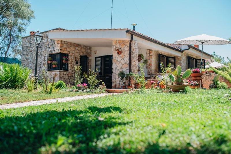 a small stone house with an umbrella in a yard at Villa Silvana tra natura e mare in Polignano a Mare