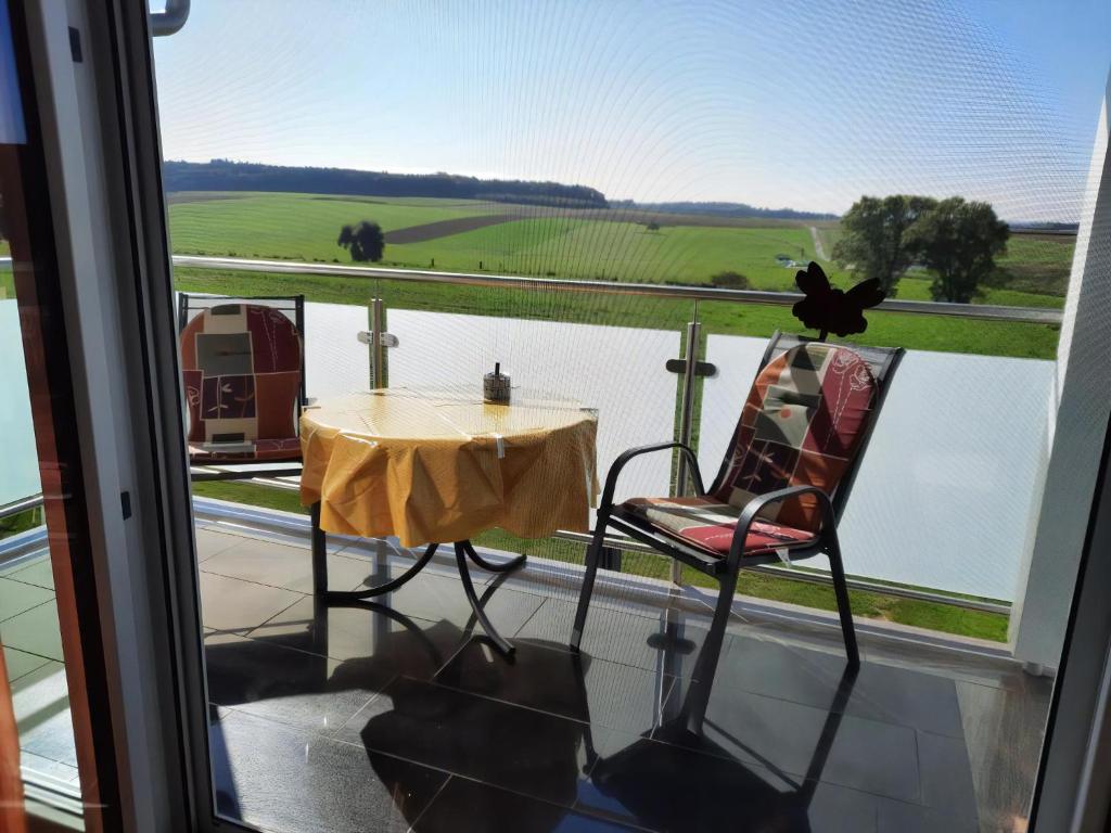 ein Tisch und Stühle auf einem Balkon mit Blick auf das Wasser in der Unterkunft Ferienwohnung Nähe Legoland Günzburg 86 qm mit Balkon in Burtenbach
