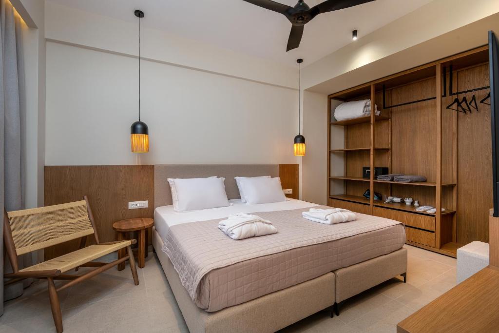 a bedroom with a large bed and a chair at Thalo "Aegean Touch Apartments" in Kardamaina