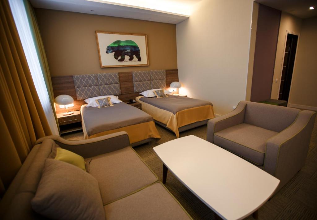 a hotel room with two beds and a couch at GREEN Which Hotel in Petropavlovsk