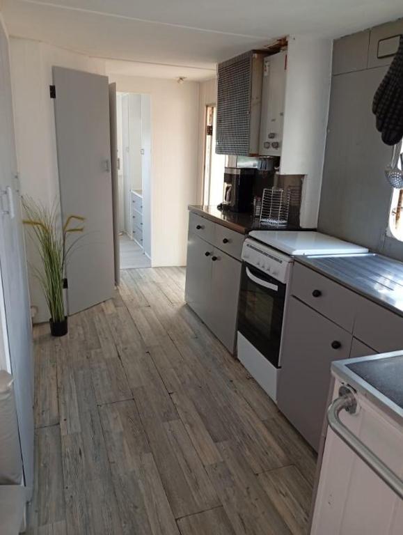 une cuisine avec des appareils blancs et un parquet dans l'établissement Mobil-Home avec piscine et jardin 1500 m2, à Valras-Plage
