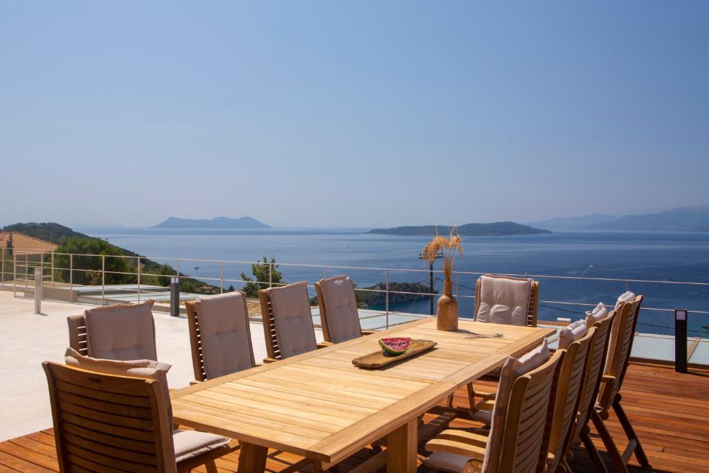 a wooden dining table with chairs and a view of the ocean at 2S Villas Resort - Cave Villas in Sivota