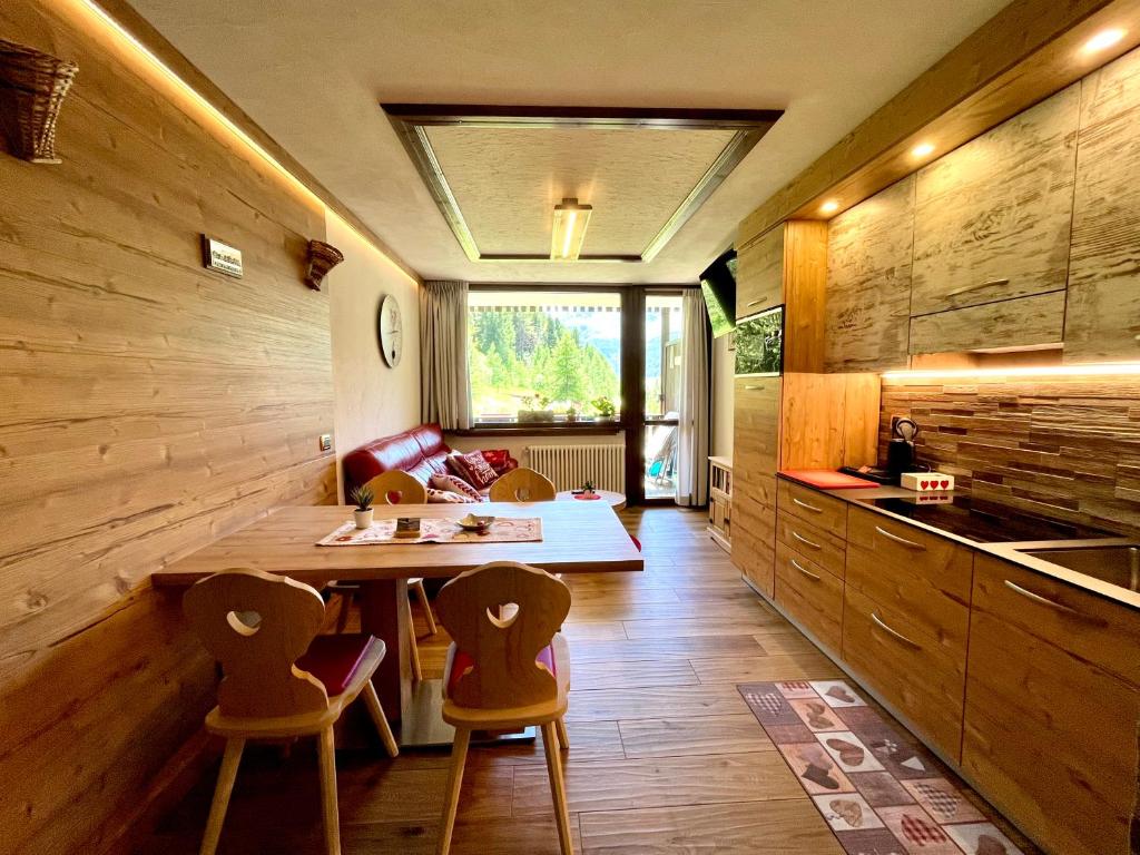 kuchnia z drewnianymi ścianami oraz stołem i krzesłami w obiekcie Home, sweet home w Livigno