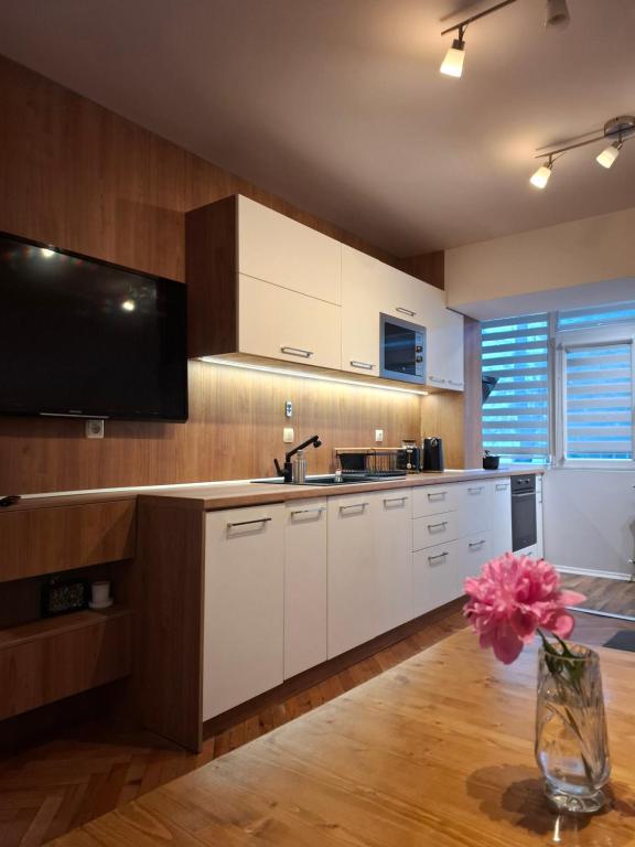 cocina con armarios blancos y TV en la pared en Апартамент за нощувки Марго, en Burgas