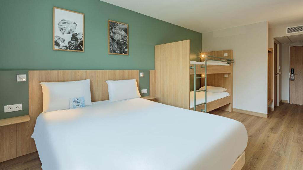 una camera da letto con un grande letto bianco in una stanza di Kyriad Anglet - Biarritz ad Anglet