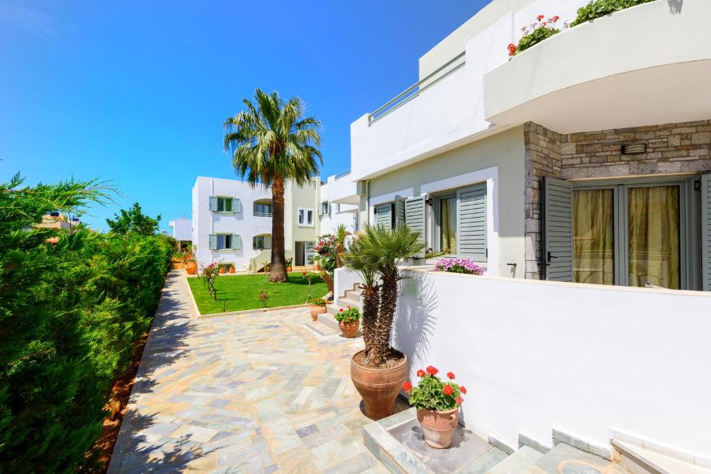 a white house with potted plants and a fence at Angela Studios Apartments in Sissi