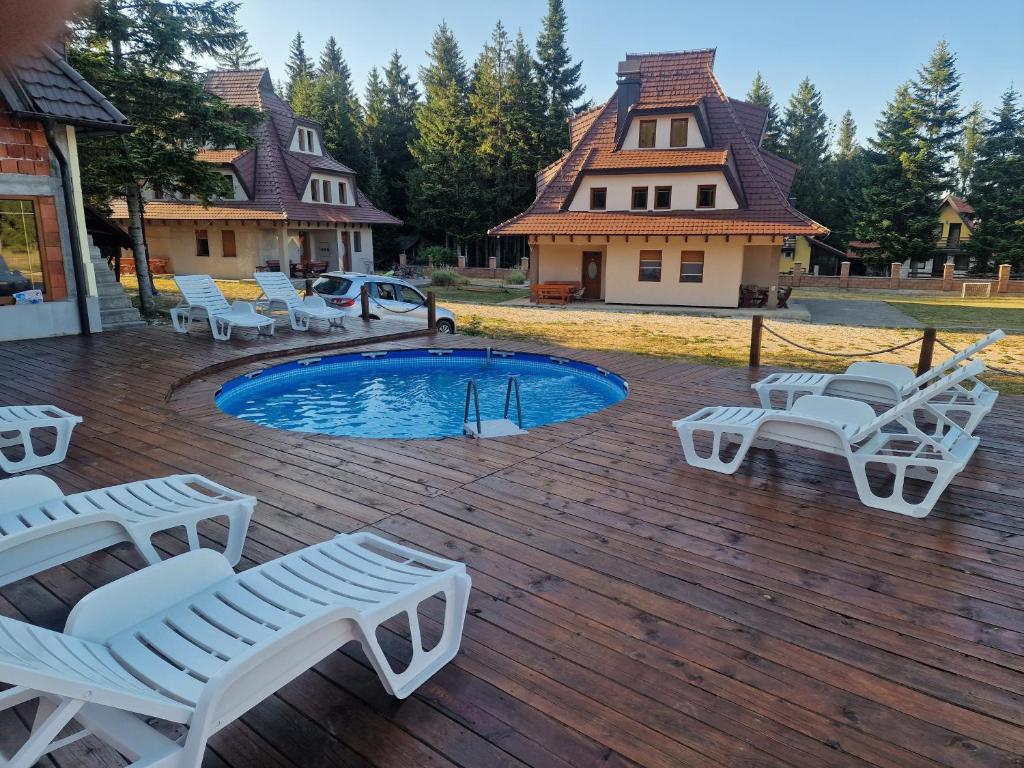 una terrazza con sedie bianche e una piscina di Vila Tri Srca a Beserovina