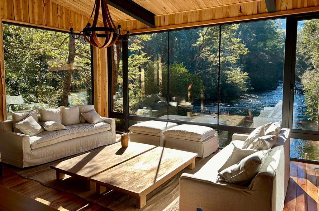 a living room with couches and a large glass window at Lodge El Remanso, Patagonia Chile in Llanada Grande