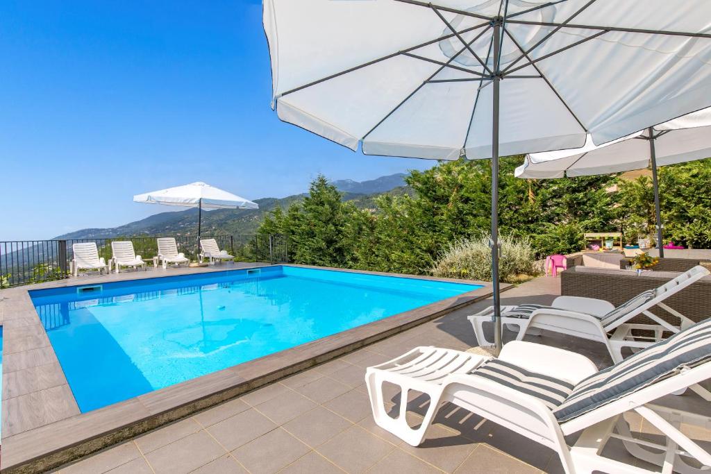 a swimming pool with two chairs and an umbrella at Villa Alternus-apartman Dora in Ičići