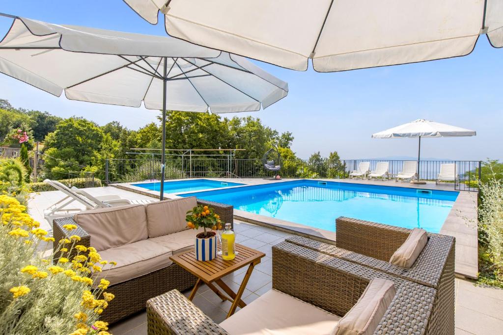 een patio met stoelen en een parasol naast een zwembad bij Villa Alternus-apartman Dora in Ičići
