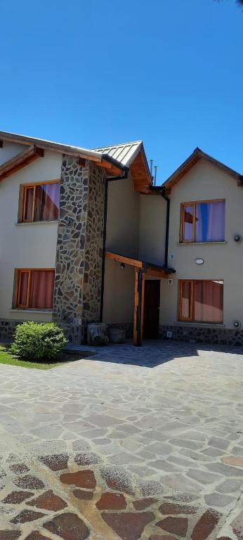 a large house with a stone patio in front of it at Cabañas Pailalen-Planta baja in Esquel