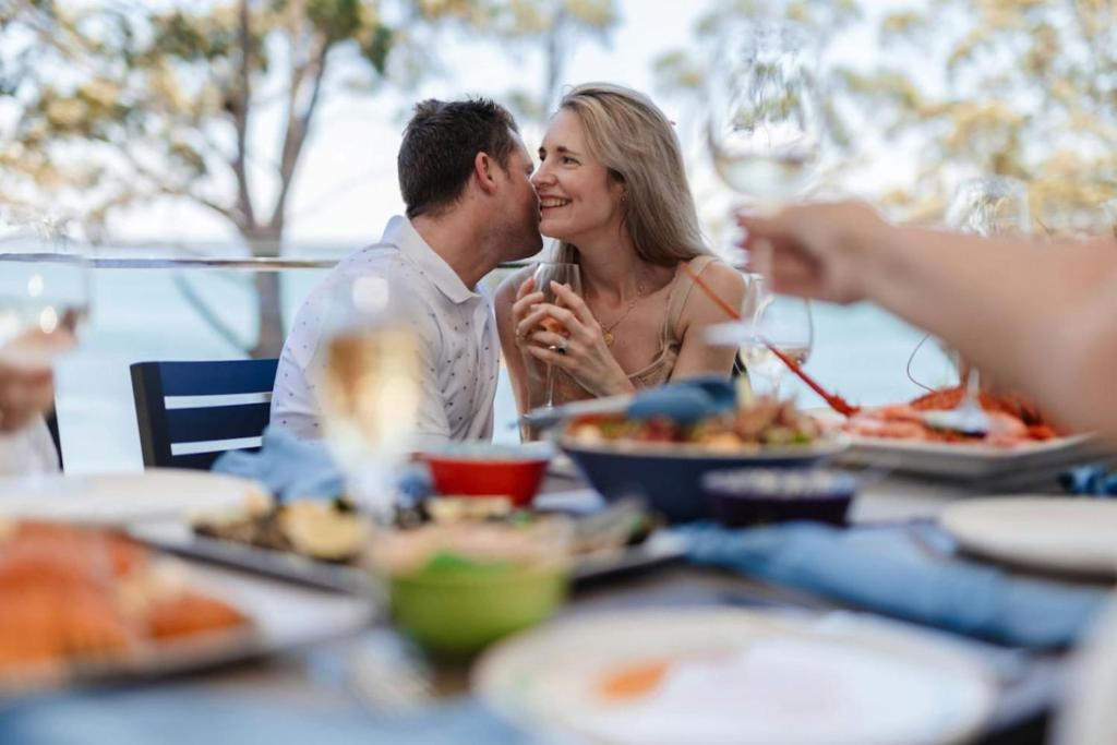 a man and woman sitting at a table eating food at Luxury Couple Escape - Vue Two in Nelson Bay