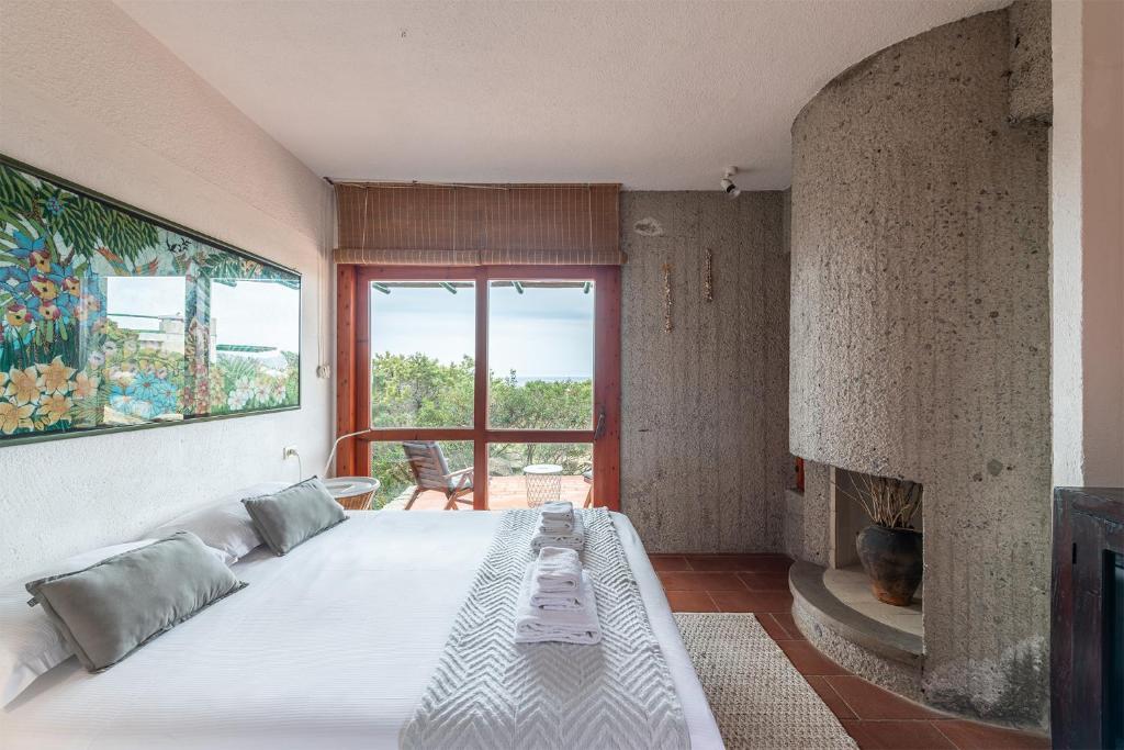 une chambre avec un grand lit et une cheminée dans l'établissement Pedra - Seaside & pool villa in wild Mediterranean, à San Stèfano