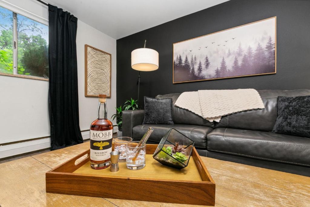 a living room with a couch and a table with a bottle of alcohol at Contemporary condo in the heart of Old Town in Fort Collins