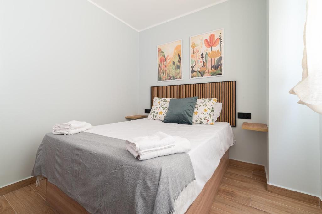 a bedroom with a bed with white sheets and pillows at Suites Deluxe By Roque in Vigo