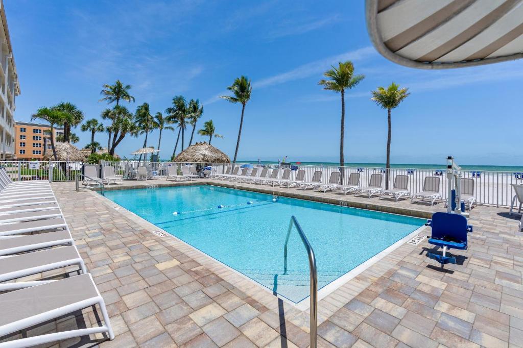 ein Swimmingpool mit Stühlen und das Meer im Hintergrund in der Unterkunft Best Western Plus Beach Resort in Fort Myers Beach