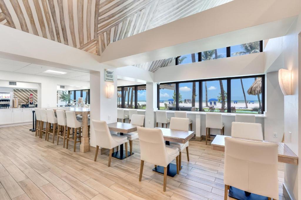 ein Esszimmer mit weißen Stühlen, Tischen und Fenstern in der Unterkunft Best Western Plus Beach Resort in Fort Myers Beach