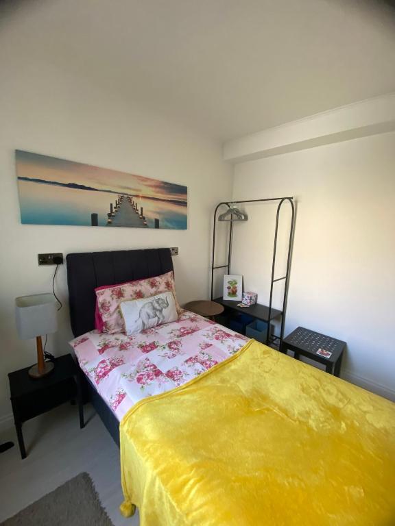 a bedroom with a large bed with a yellow blanket at Mel House in Glenrothes