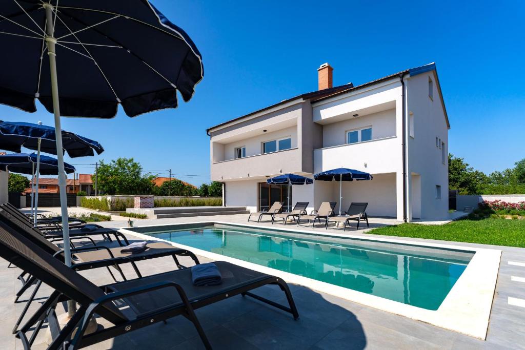 a villa with a swimming pool and patio furniture at MY DALMATIA - Villa Campi Dalmatia with private heated pool and sauna in Galovac