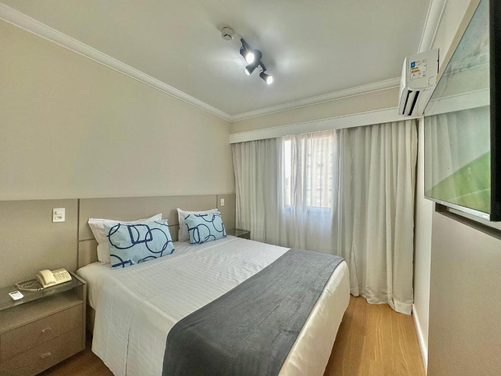 Un dormitorio con una cama grande con almohadas azules. en Flat Conforto Andar Alto c/ Varanda | The Palace, en São Paulo