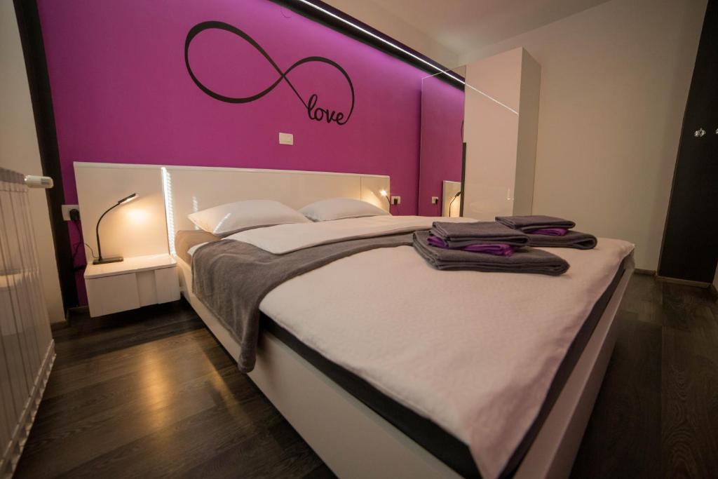 - une chambre avec un grand lit et un mur pourpre dans l'établissement Apartment Andolsek, à Bohinj