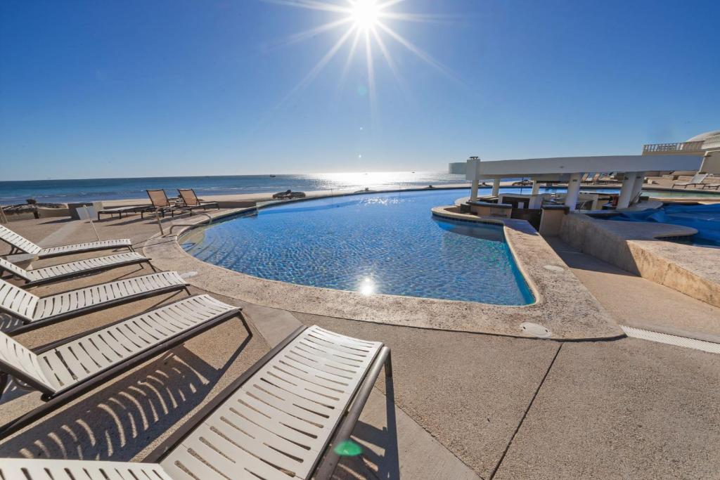 a swimming pool with lounge chairs and the ocean at Las Palmas 4BR 4BA Penthouse Ocean View 703 in Campo del Medio