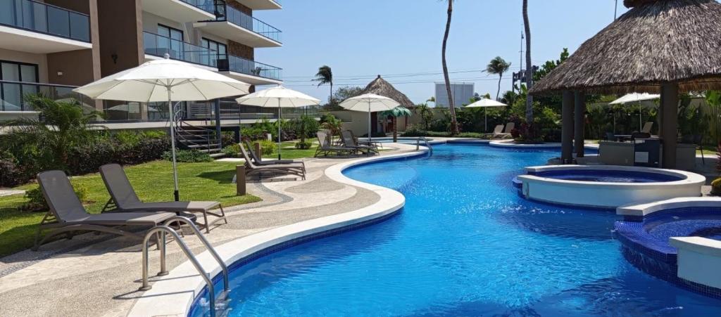 a swimming pool with chairs and umbrellas at a resort at Descanso en ACAPULCO DIAMANTE in Acapulco