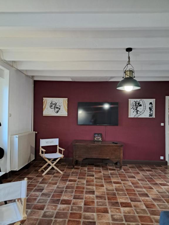 a room with a table and a flat screen tv at Gîte La Maison des Arts in Jaunay-Marigny