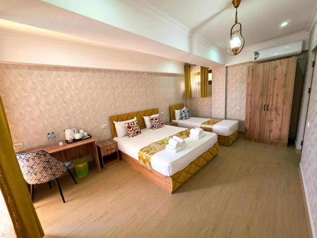 a hotel room with two beds and a table and a chair at Samarkand Imron Hotel in Samarkand