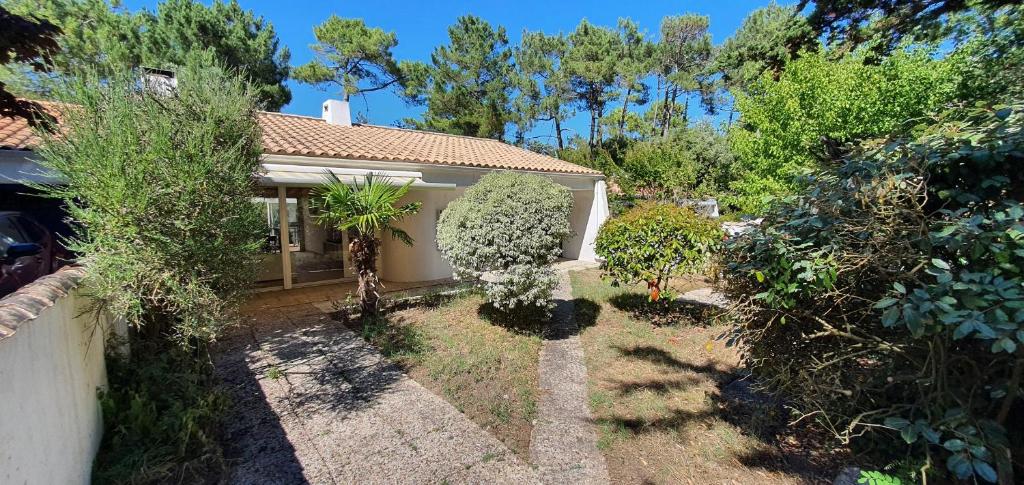 a house with a yard with trees at Charmante maison de plain pied rénovée et climatisée en lisière de forêt in Saint-Jean-de-Monts