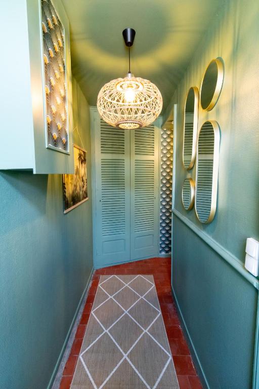 un couloir avec un lustre et un sol rouge dans l'établissement Maison de ville au cœur de Saint Pierre en Auge, à Saint-Pierre-sur-Dives