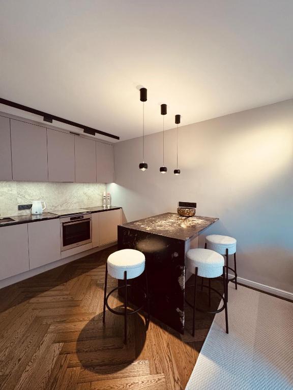 a kitchen with a large island with white cabinets and stools at Portside living in Klaipėda