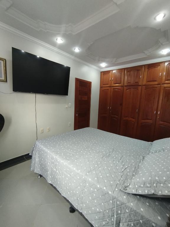 a bedroom with a bed and a flat screen tv at Quarto Privativo Rains Santos in Belém