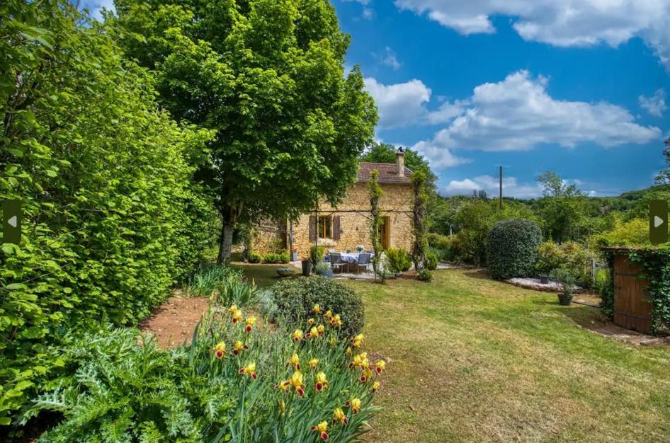 an old stone house in the middle of a garden at Le Cottage dans la Vallée des 5 châteaux in Vézac