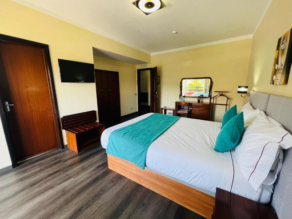 a hotel room with a large bed and a television at Hotel Colmeia in Monte Real