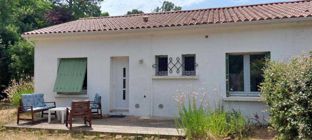 a small white house with a table and chairs at Les Lagures - PLAGE A PIED - Maison 3 chambres - en lisière de forêt in Longeville-sur-Mer