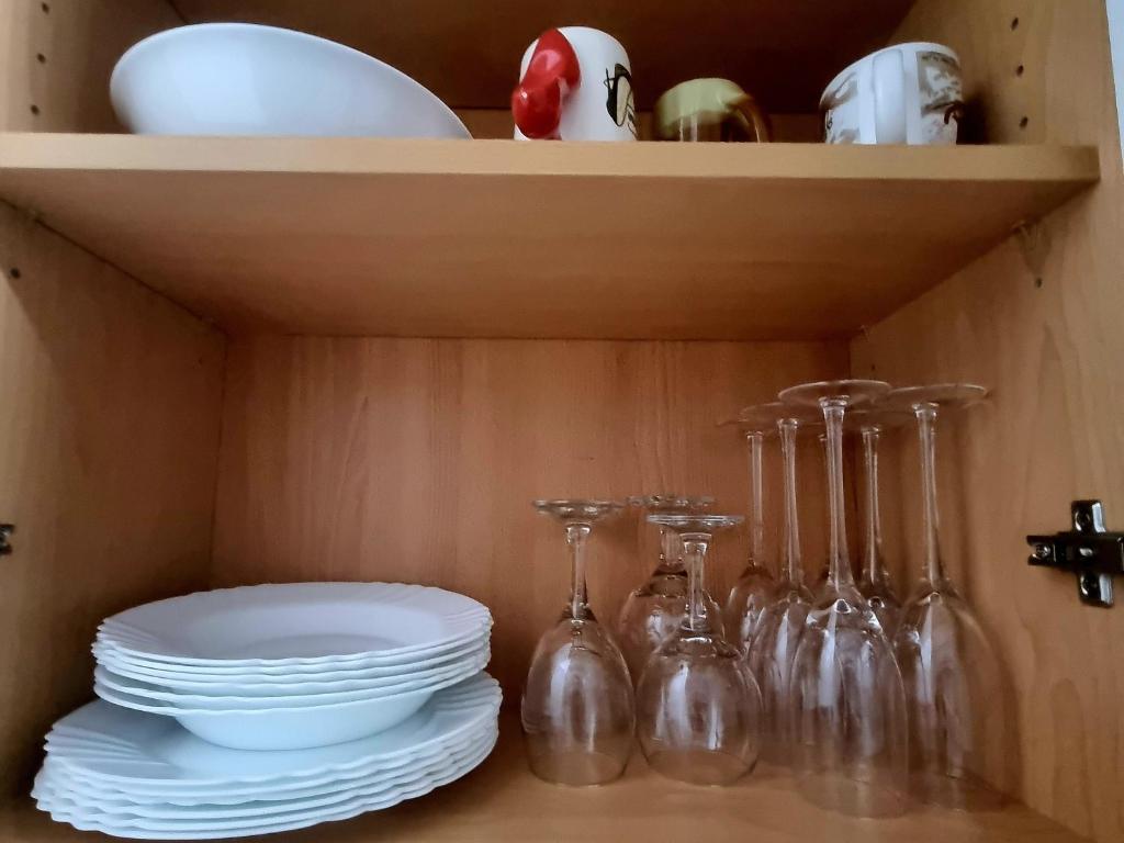 Un estante con platos, vasos y fuentes encima. en Lina's Apartment -Modern & Cozy Central Skopje, en Skopje